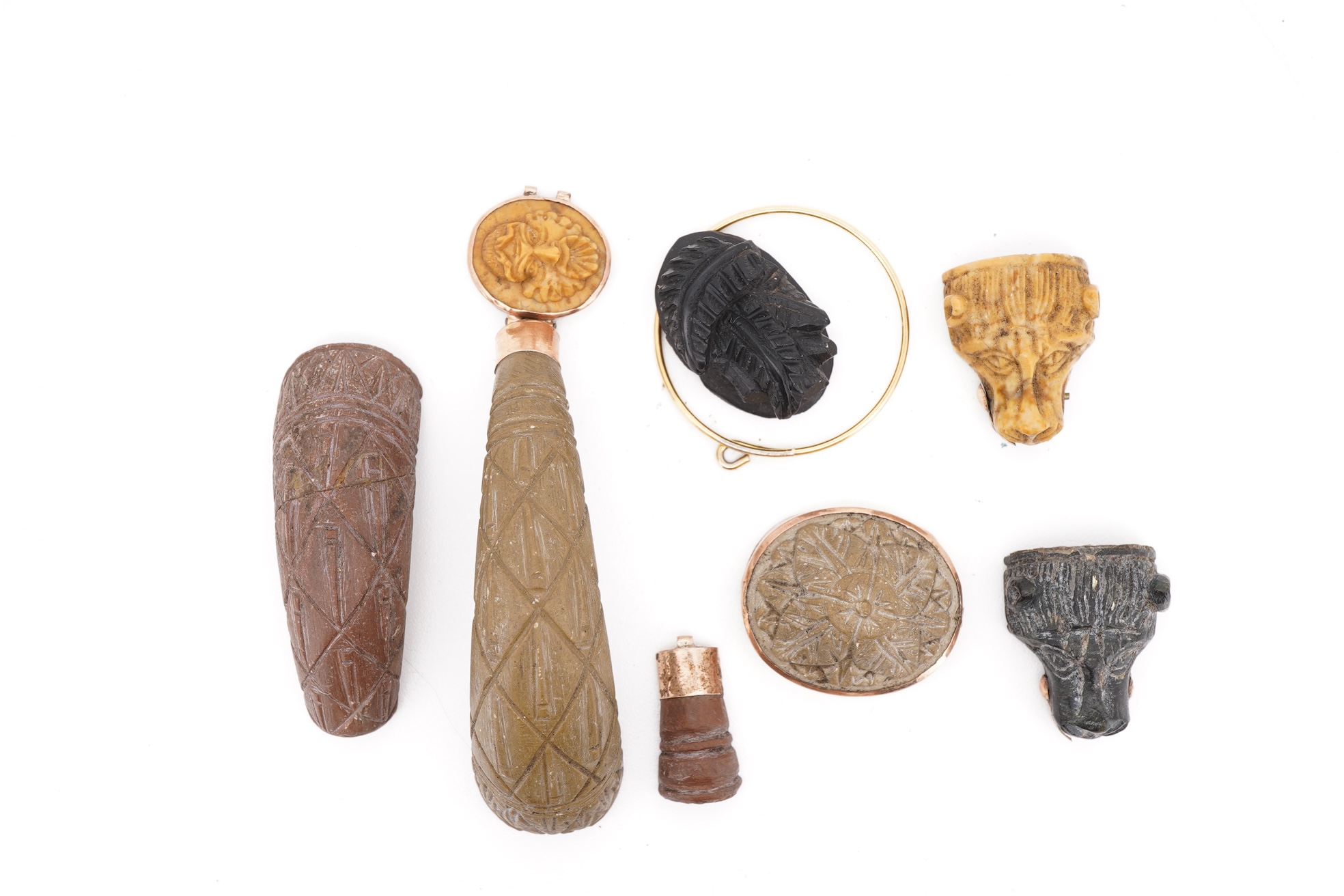A collection of carved lava fragments, 19th century, once forming a bangle, the fragments variously carved with abstract floral motifs, lion's heads, and a theatrical mask, largest 6.2cm, Condition: fragmentary, but carv